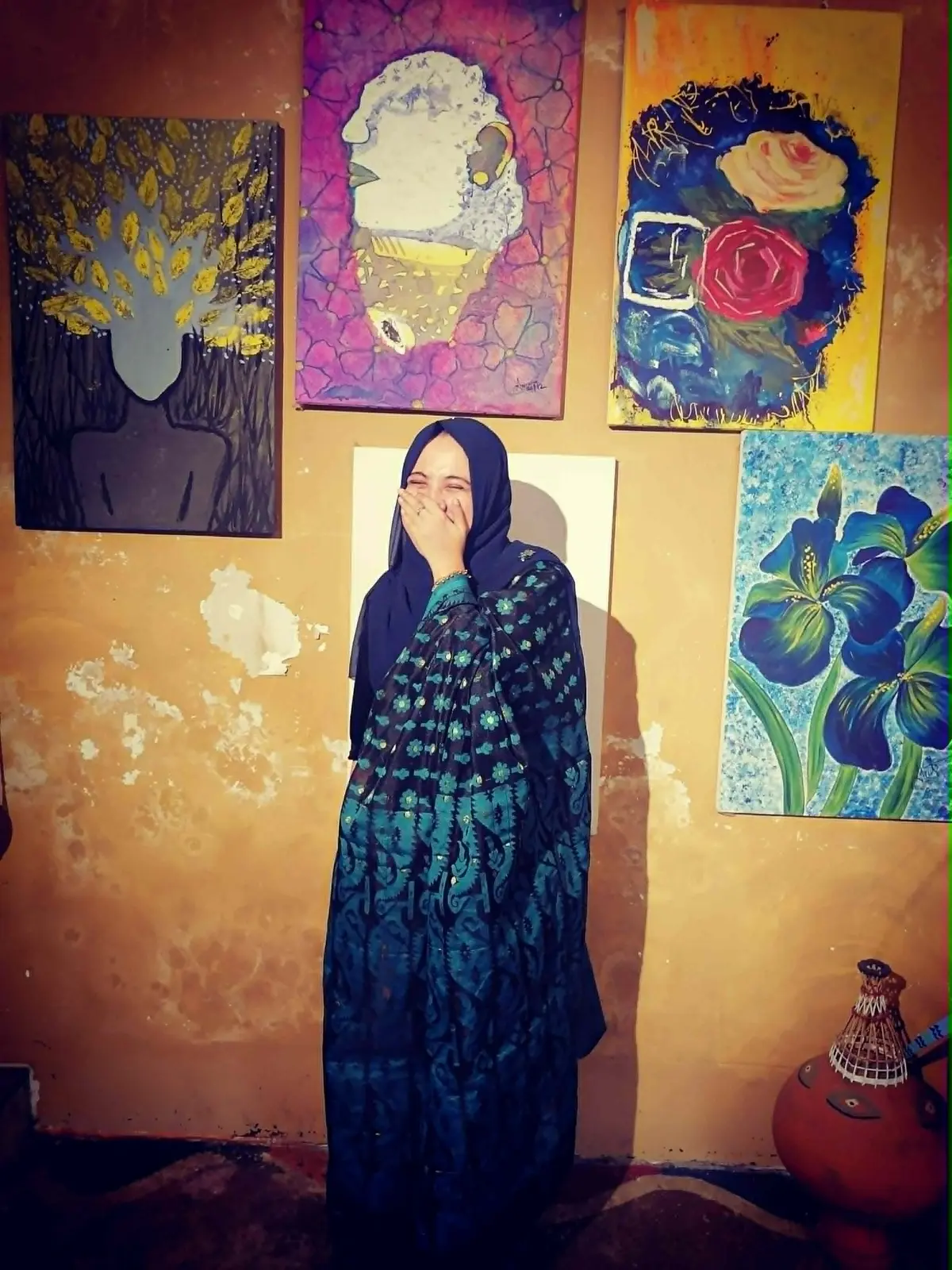 Tajrian laughing beside colorful paintings