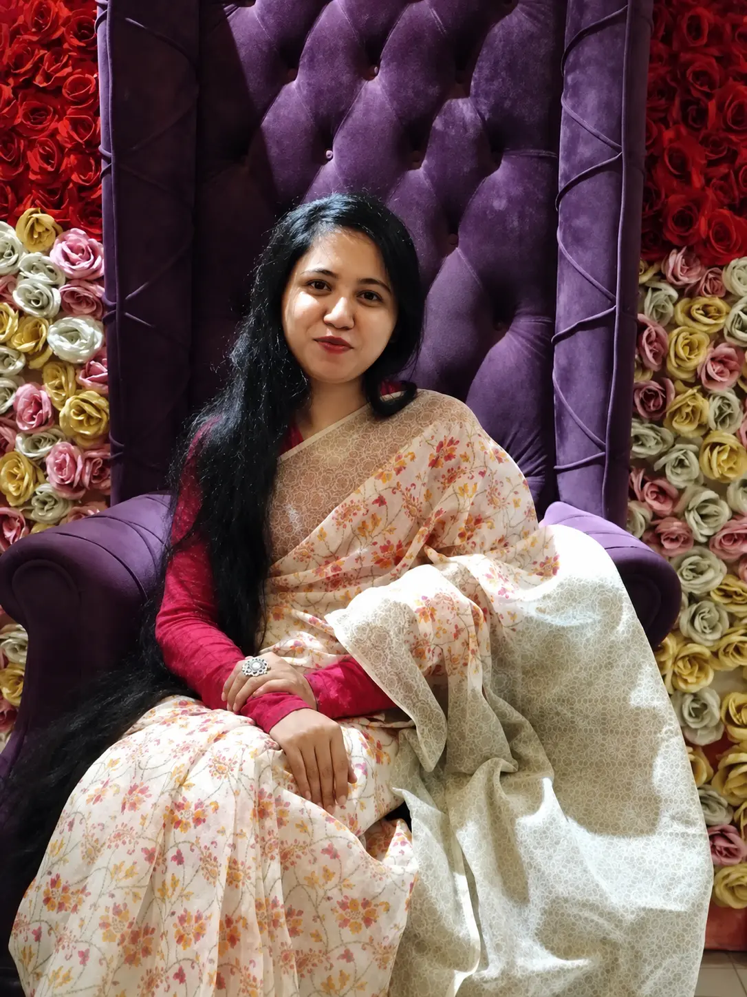 Tajrian seated against a wall of roses